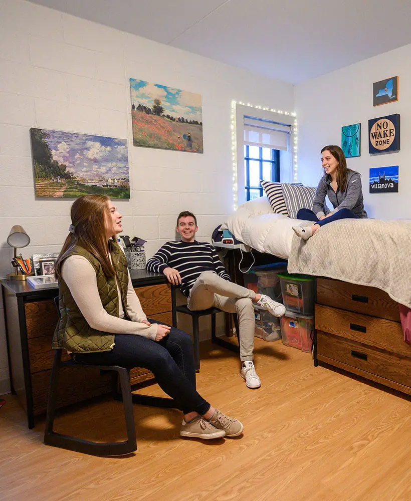 Three students sit in residence hall room talking